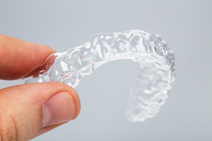 Hand holding a translucent upper essix retainer - Grande Prairie Dentist - Boisson Dental Group